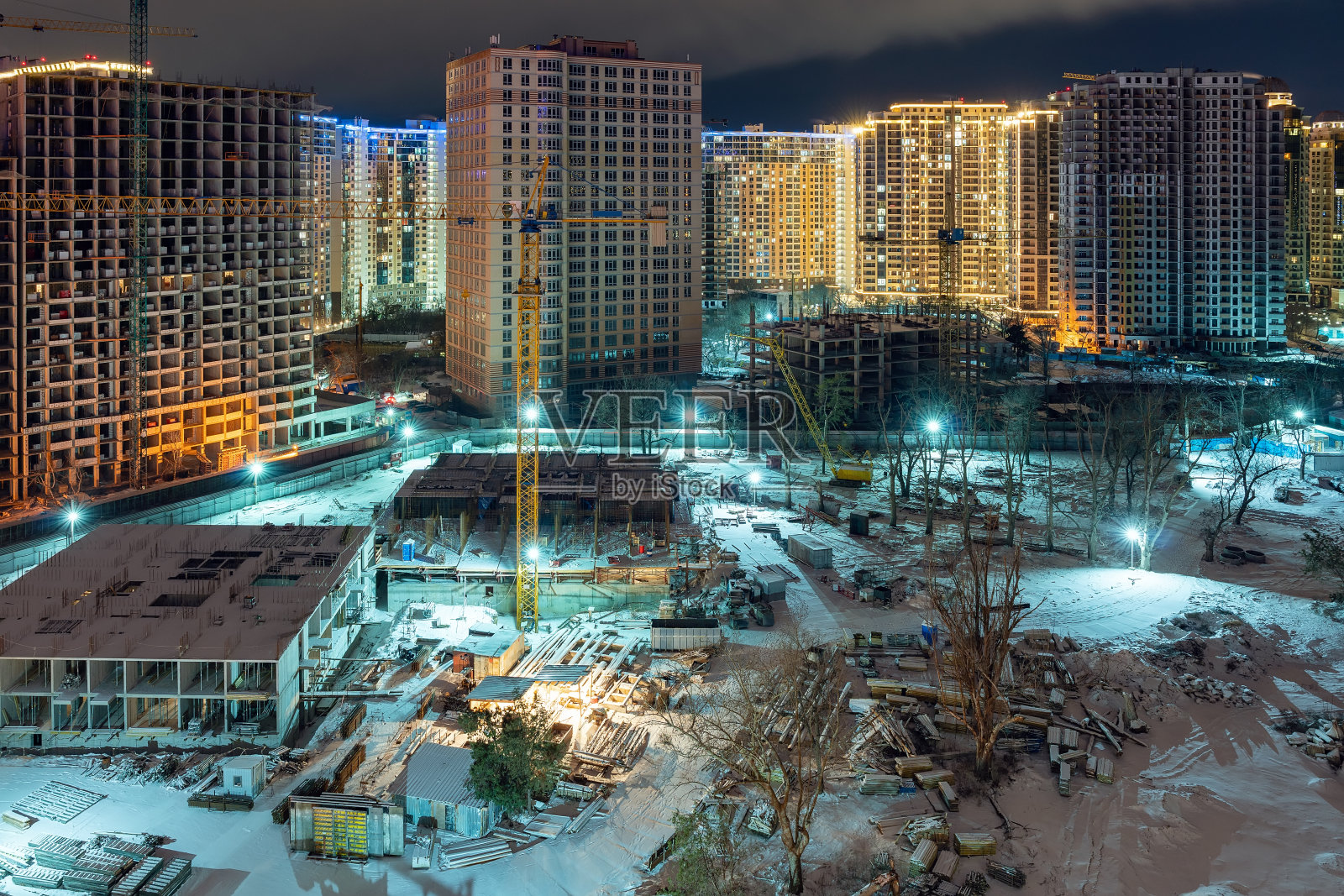 冬季夜晚的工地、起重机和未完工的多层房屋照片摄影图片