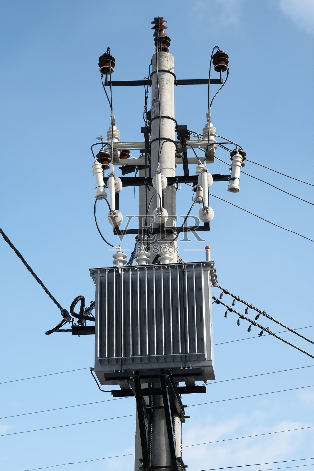 变压器安装在一根杆子上，背景是蓝天照片摄影图片