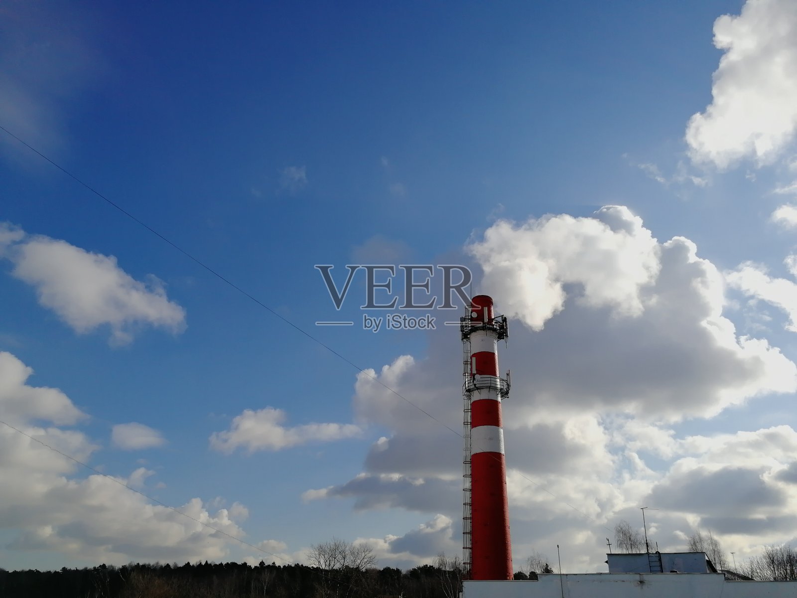 红色的锅炉烟囱在冬天的背景与蓝色的天空与云彩照片摄影图片