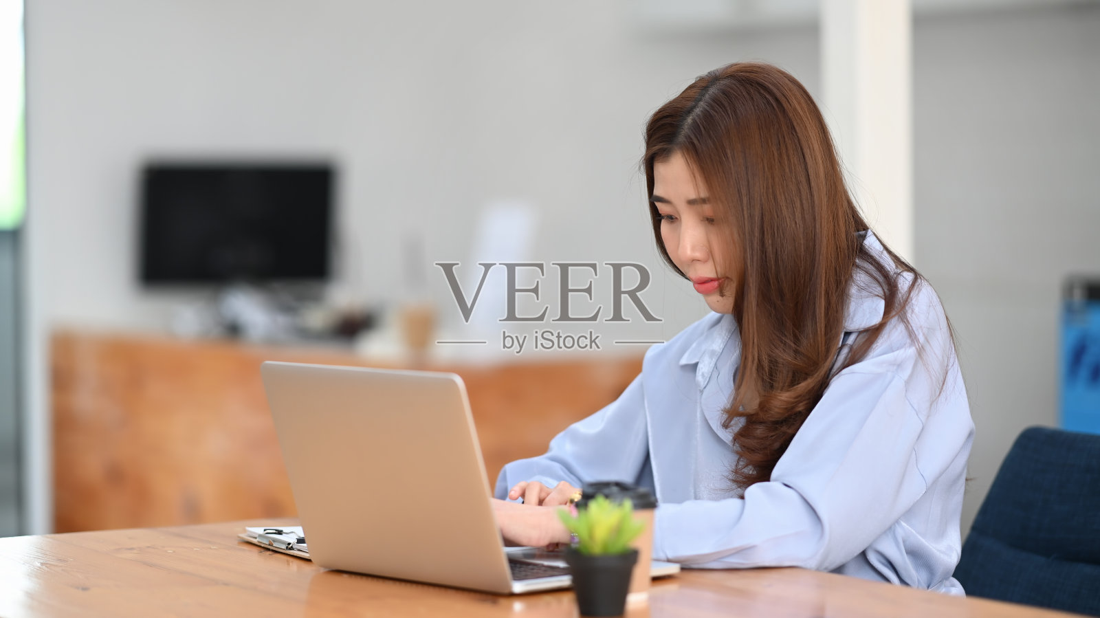 女性办公人员在办公桌上专注于笔记本电脑工作。照片摄影图片