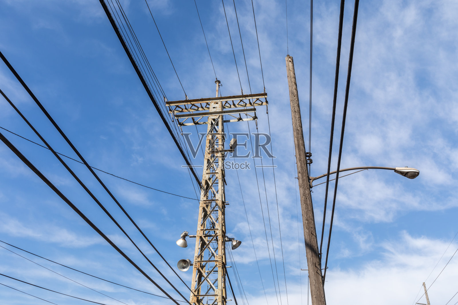 查看金属和木材电力结构与电缆，街道和聚光灯对蓝天与云照片摄影图片