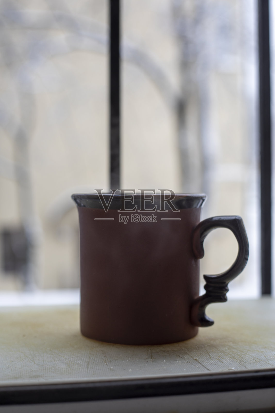 用瓷杯端着一杯饮料放在一个安静的靠近窗户的地方，在一个冬日里，一级防范禁闭照片摄影图片