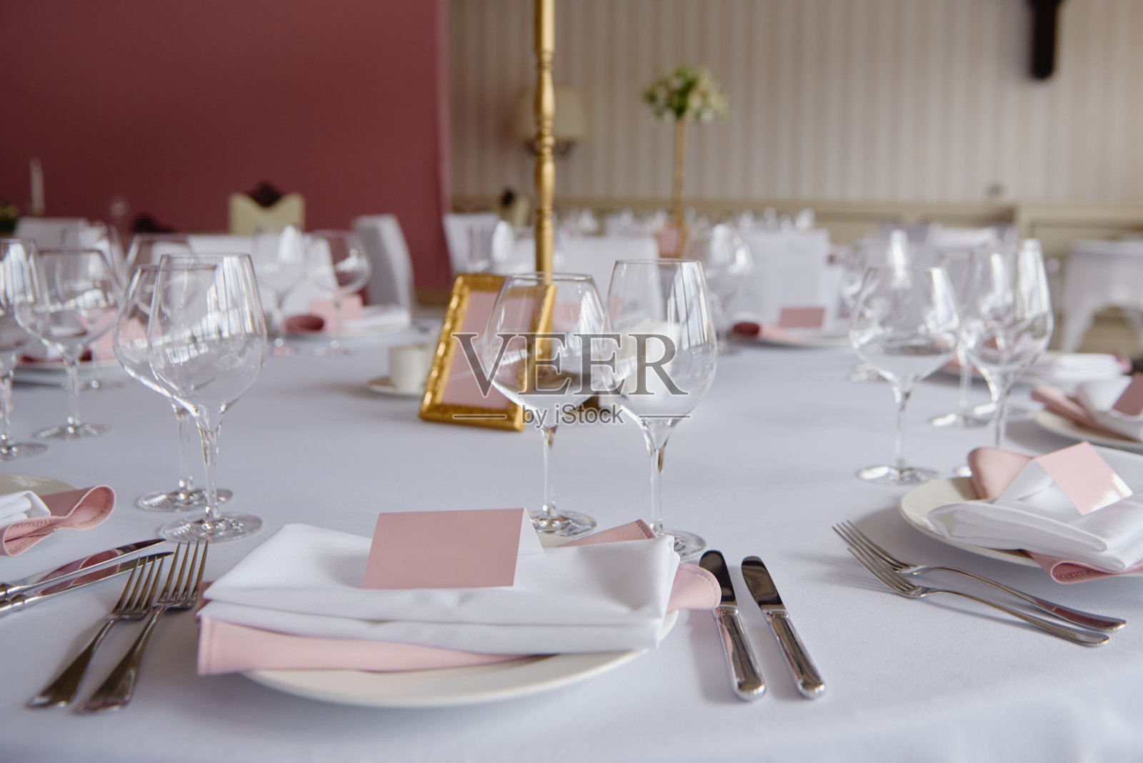 桌子上放置空白的客人卡，盘子上有粉色和白色的餐巾和餐具，复印空间。婚宴场地设置。餐厅婚宴餐桌照片摄影图片
