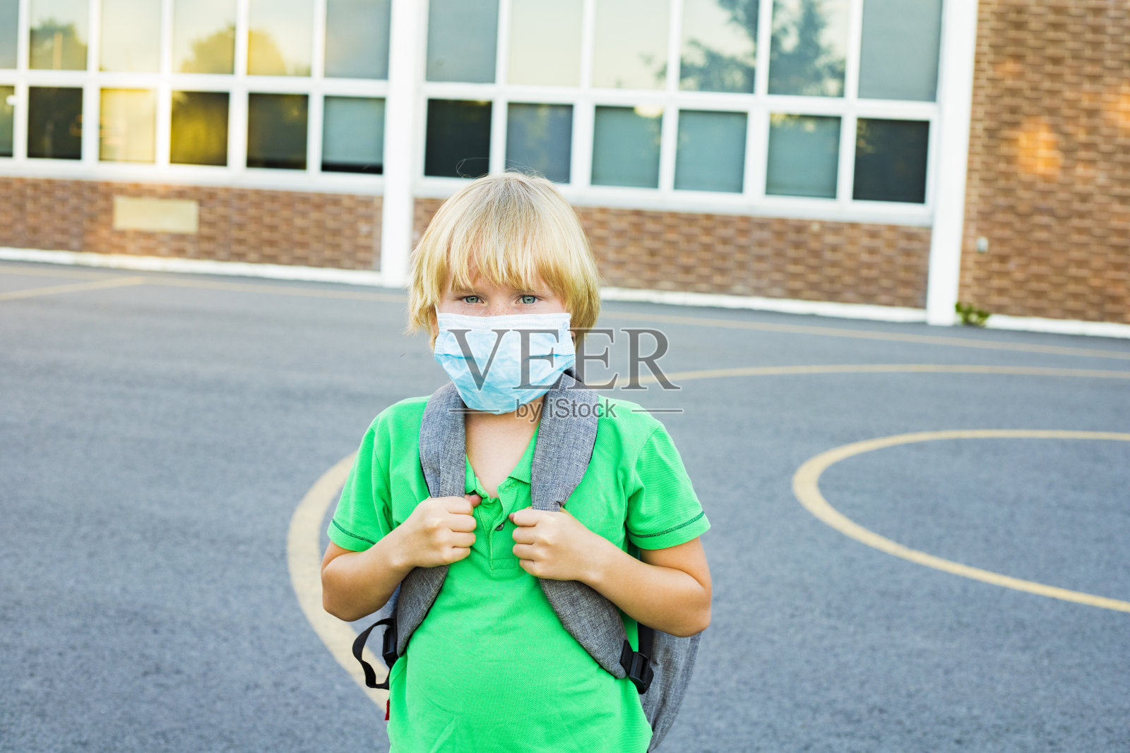 冠状病毒爆发期间，在学校附近戴口罩的儿童。照片摄影图片