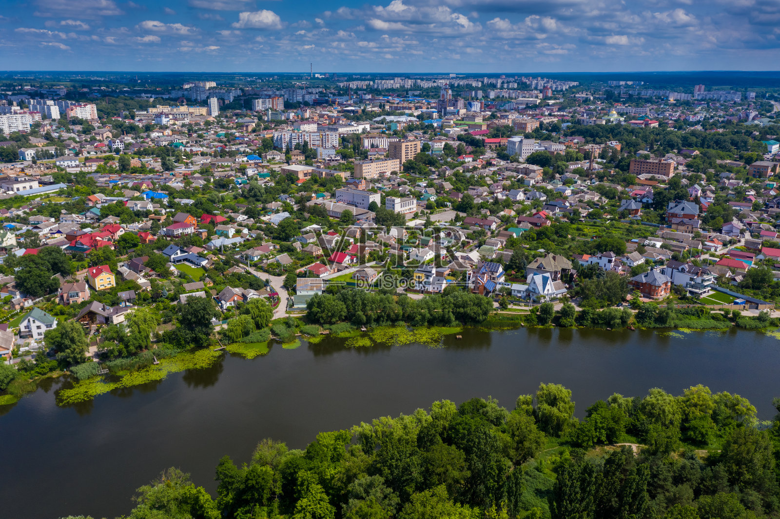 美丽的夏季俯瞰城市。屋顶，河流，绿树。照片摄影图片