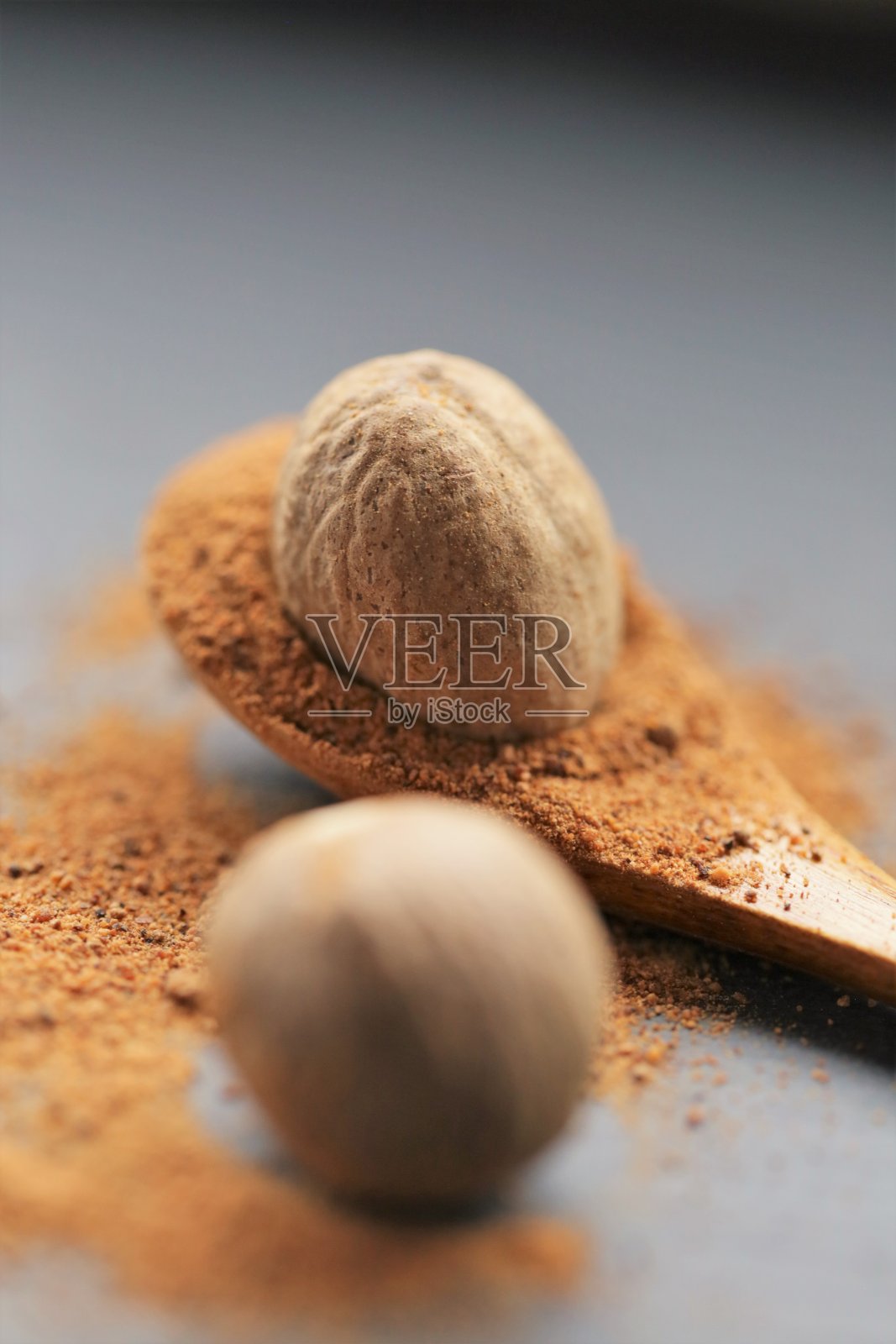 肉豆蔻香料。整个和磨碎的肉豆蔻放在一个木勺里，背景是席夫特写。香料和香草概念。食品成分。肉类和烘焙用香料。肉豆蔻粉照片摄影图片