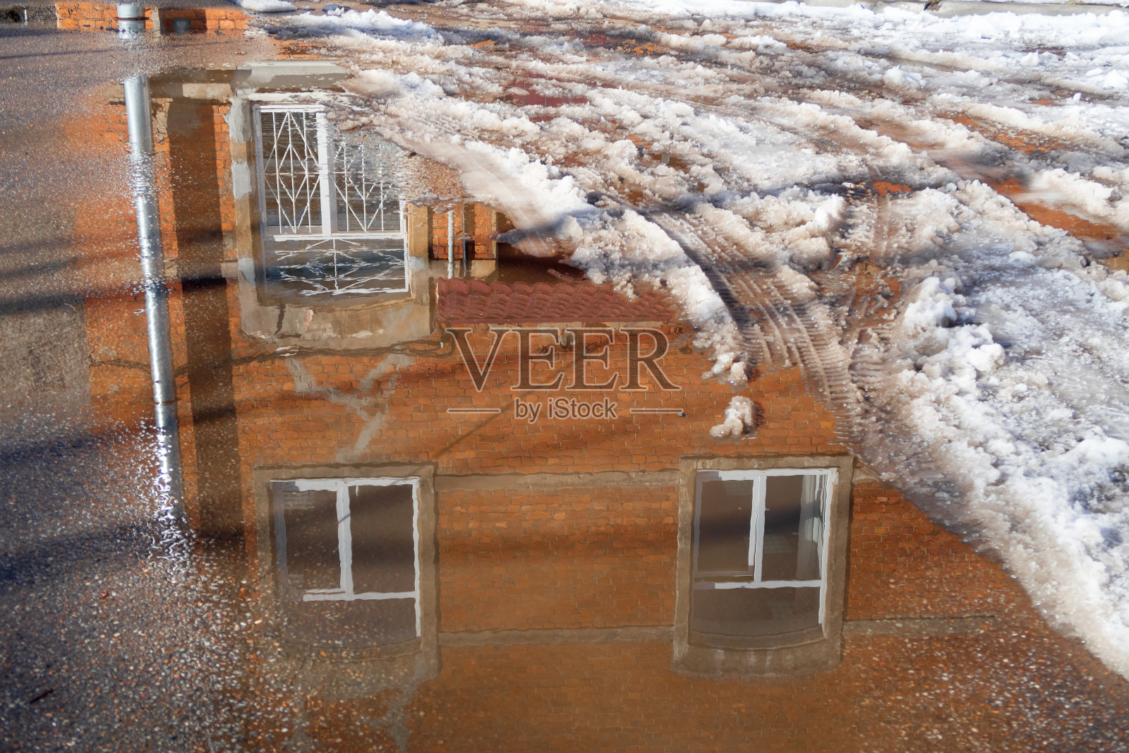 早春的城市街道上有融雪和水坑与倒影的建筑照片摄影图片