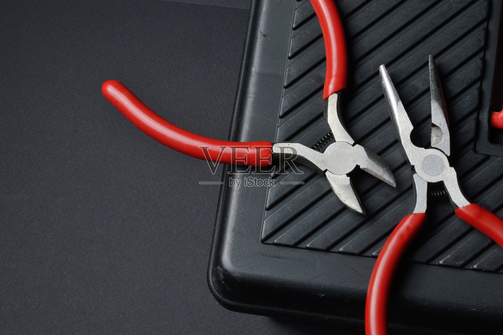 小钳子和钳子躺在一个封闭的工具箱上。从以上观点。照片摄影图片