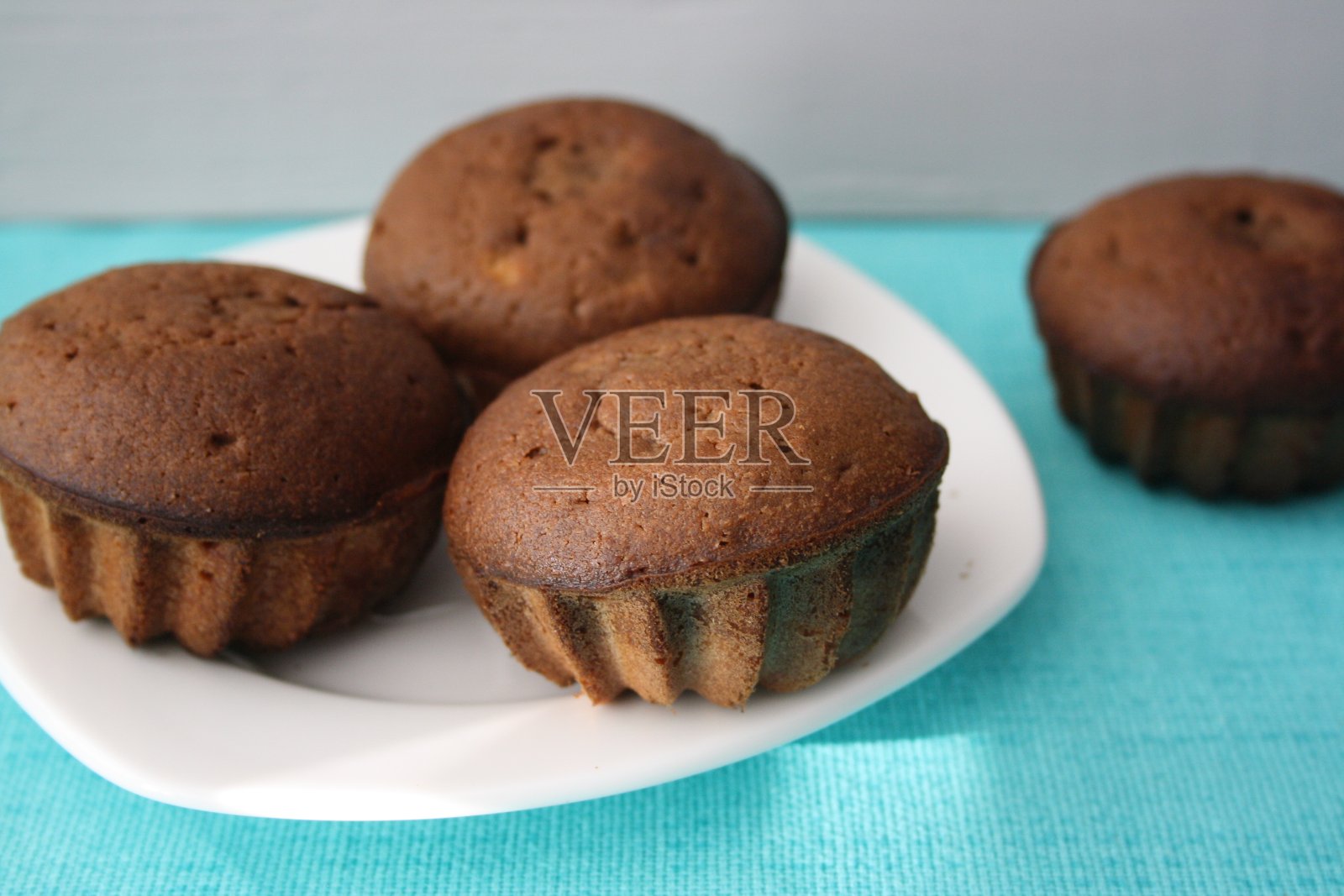 白色盘子上的一个小形状的纸杯蛋糕。照片摄影图片