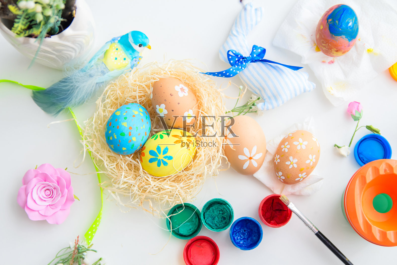 五彩缤纷的复活节彩蛋，手工制作的燕窝，复活节装饰品，油漆和画笔在白色的桌子上。节日复活节背景。照片摄影图片