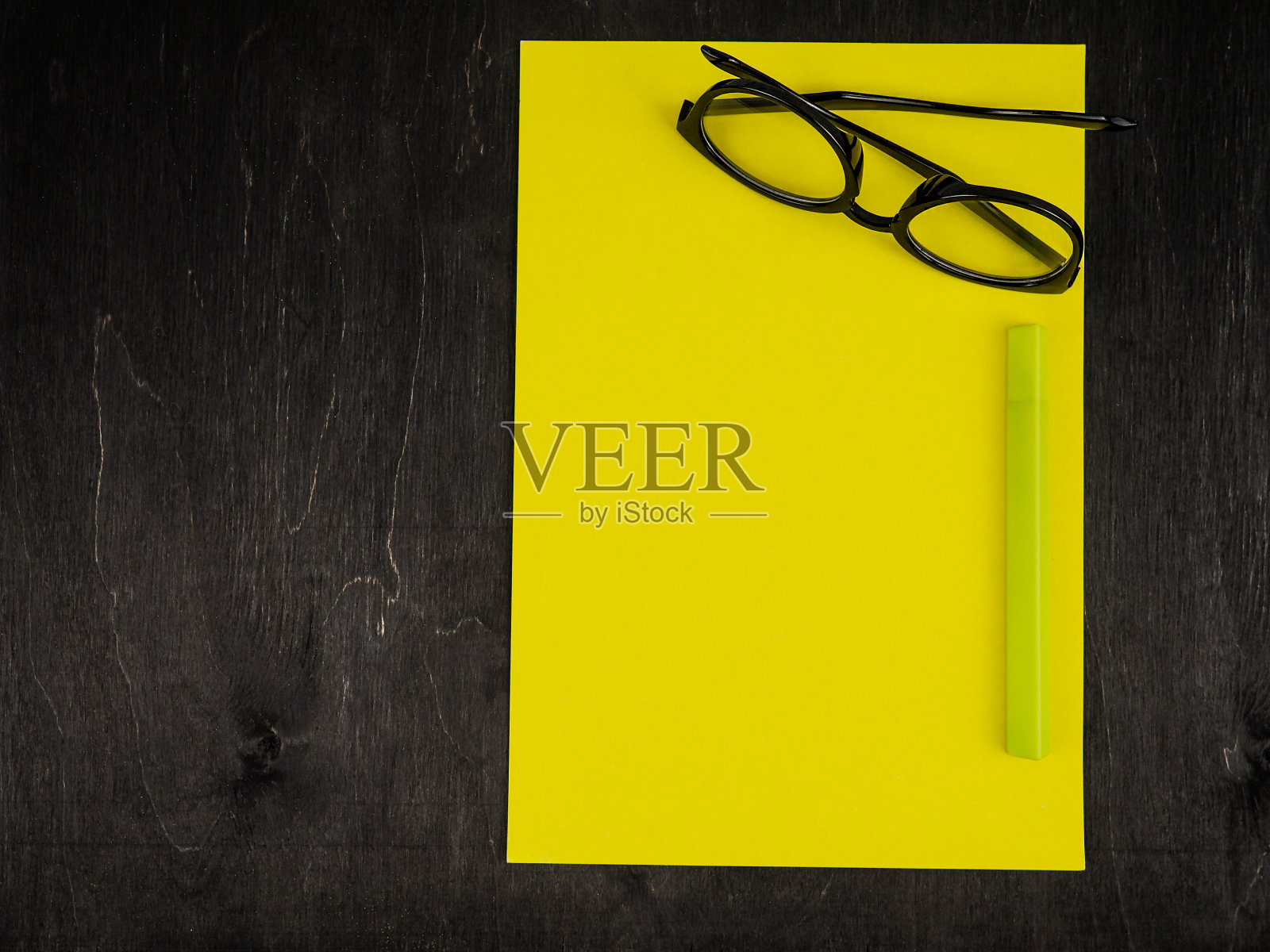 空白的黄色纸，眼镜，钢笔在黑色的背景。放置你的文本。照片摄影图片