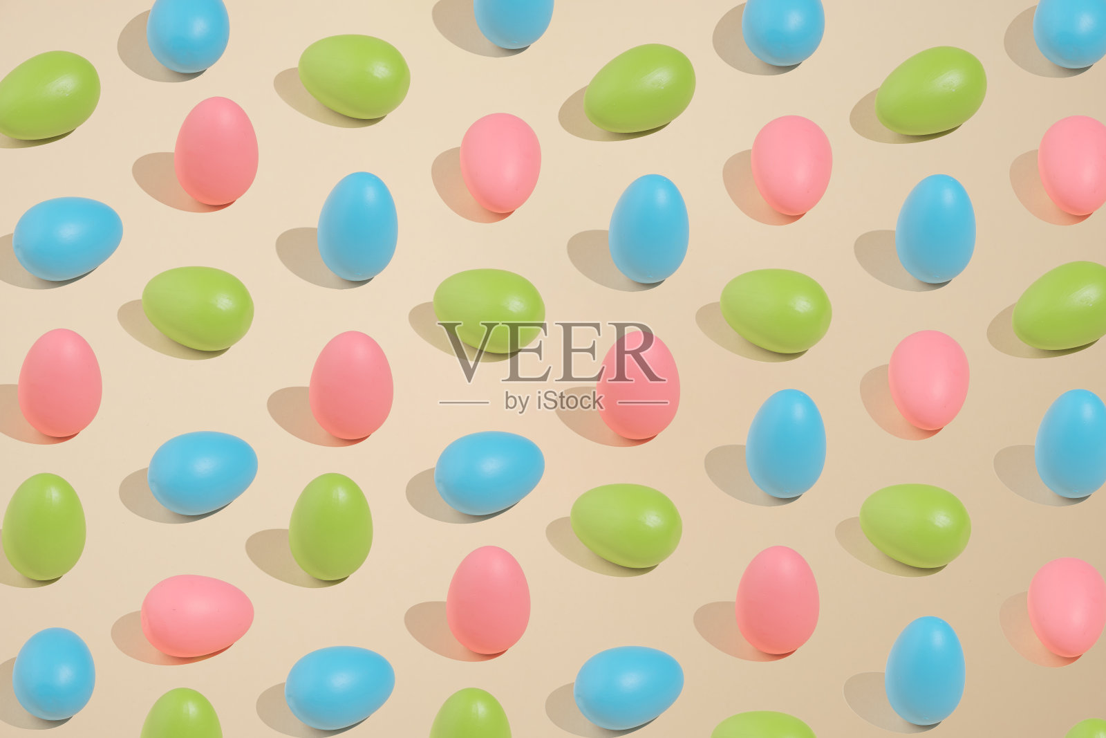 好玩的彩色复活节图案，粉红色，绿色和蓝色的蛋在米色的背景。最小的概念风格。照片摄影图片