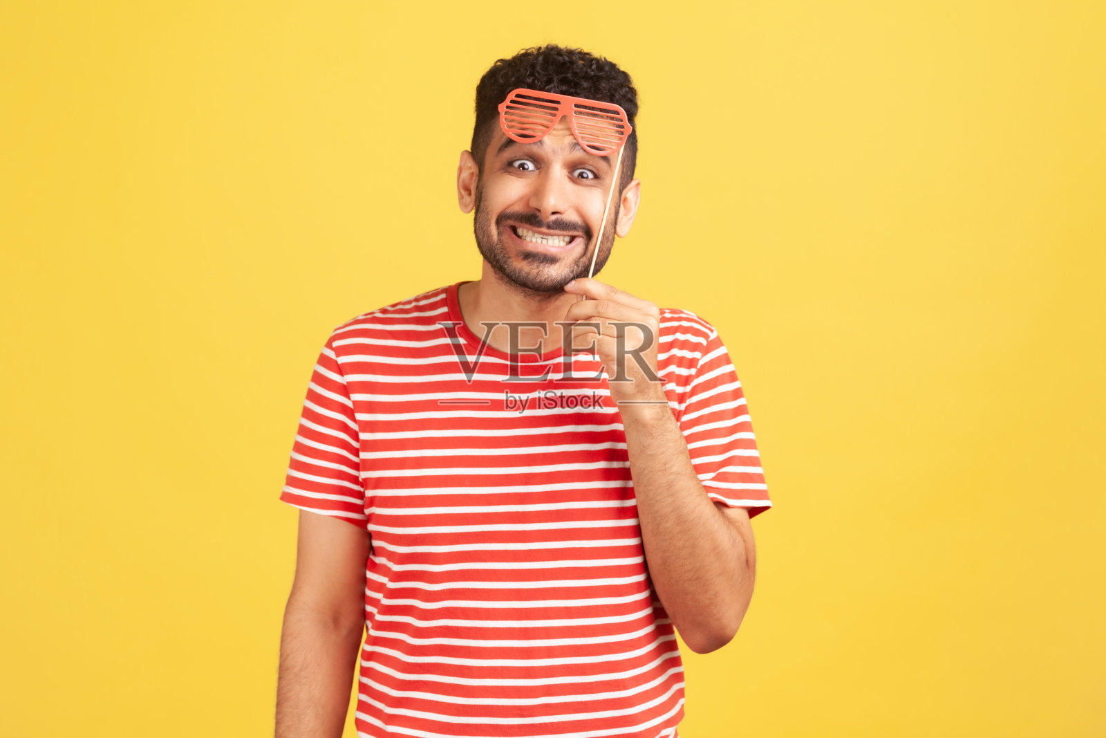 开心的男子手持派对玩具面具对着镜头微笑照片摄影图片