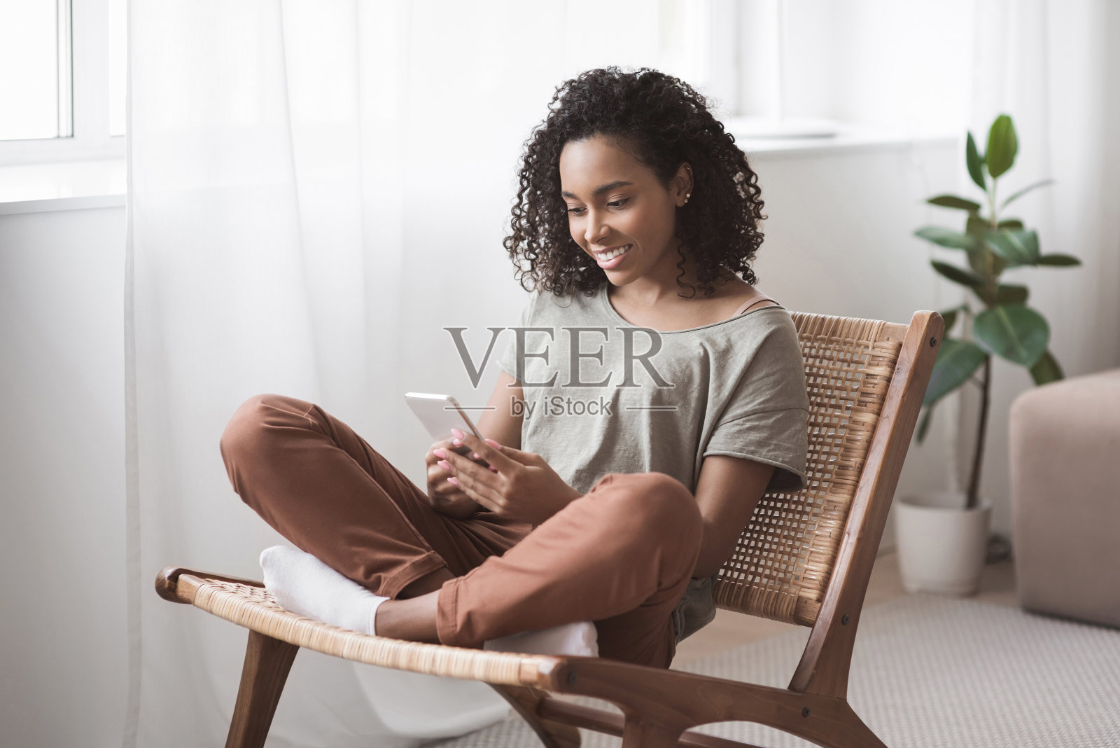 在家里使用智能手机的女性。女孩用手机发短信照片摄影图片