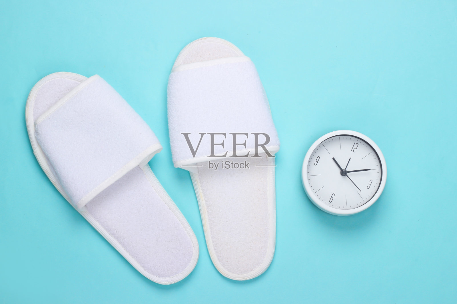 时间睡觉。蓝色背景的睡鞋和时钟。俯视图照片摄影图片