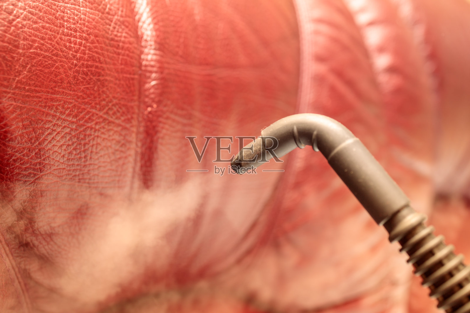 蒸汽从蒸汽发生器的喷嘴出来，背景是一个皮沙发照片摄影图片