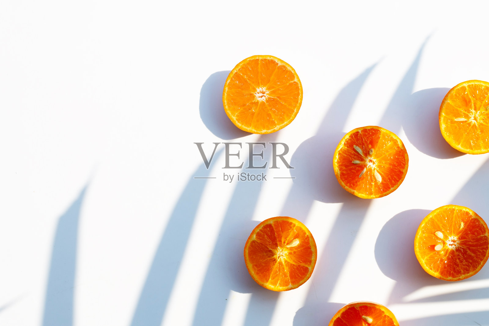 高维生素C，多汁甜。新鲜的橙色水果在白色的背景与叶片阴影照片摄影图片