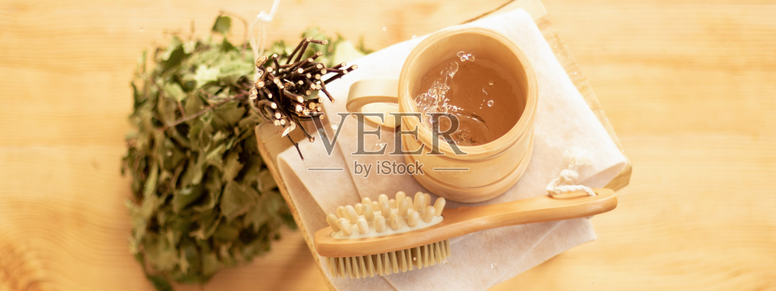 沐浴在桑拿中放松身心。蒸汽房的配件，木制家具，浴室扫把和水在杯子里。照片摄影图片