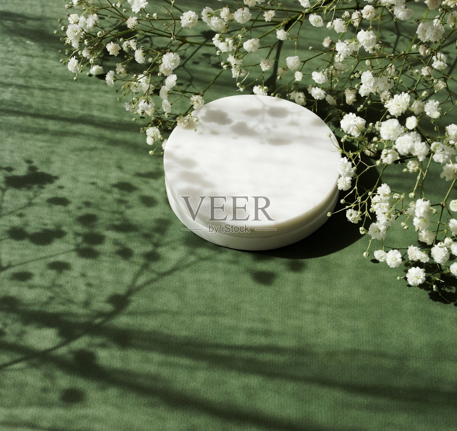 大理石讲台的化妆品产品介绍和白花顶视图在绿色背景与阳光阴影。副本的空间。白色大理石底座背景。照片摄影图片