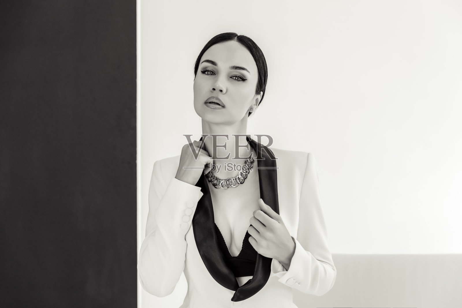 穿着西装的性感女商人在一个白色照相馆里。坐在白色沙发上的女人照片摄影图片