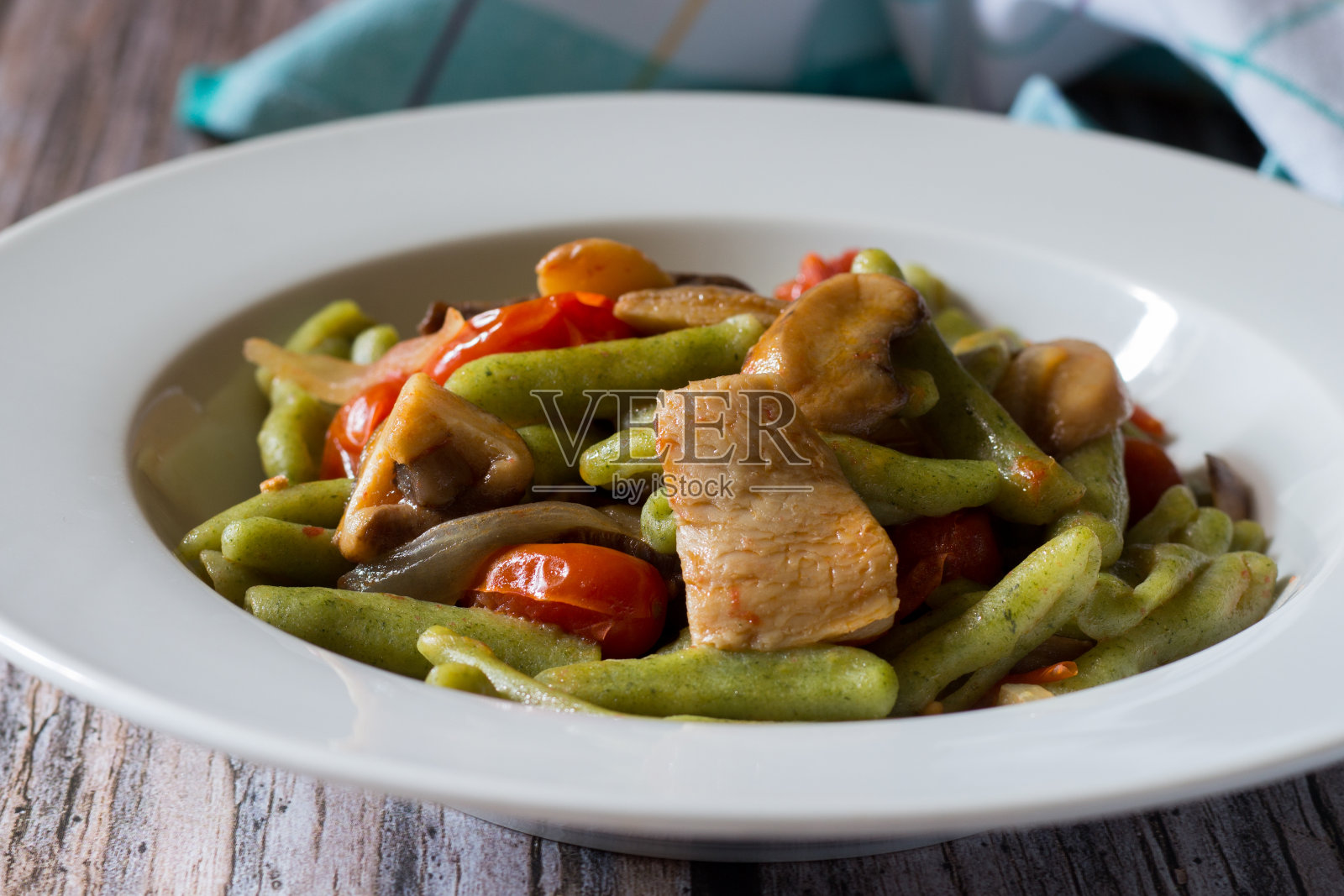 Cavatelli菠菜。典型的意大利自制面食配樱桃番茄和蘑菇。照片摄影图片