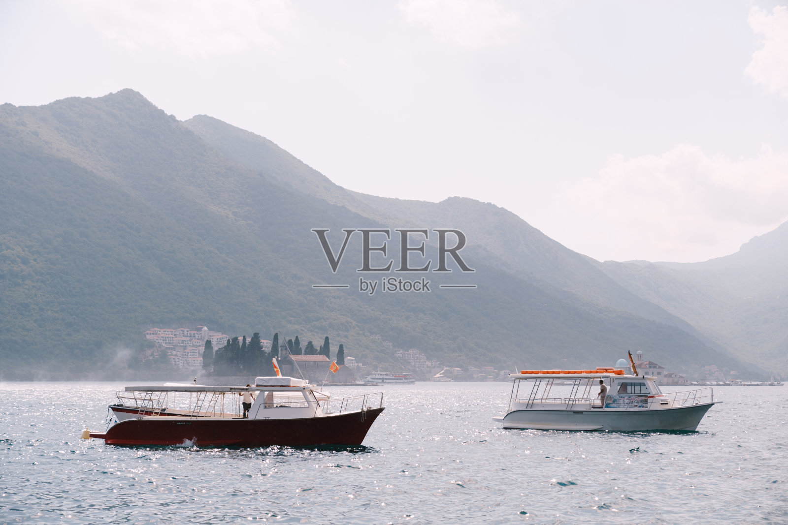 在黑山佩拉斯特市的群山和岛屿的背景下，两艘摩托艇。照片摄影图片