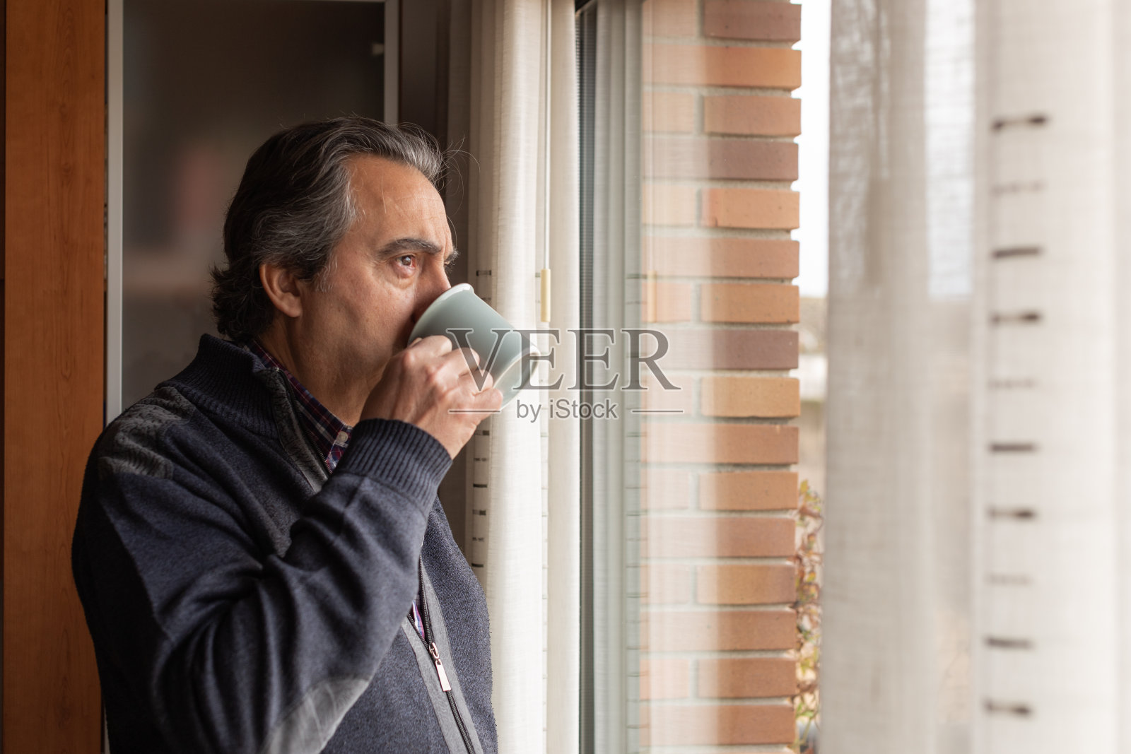 一个带着鬼脸往窗外看的男人照片摄影图片