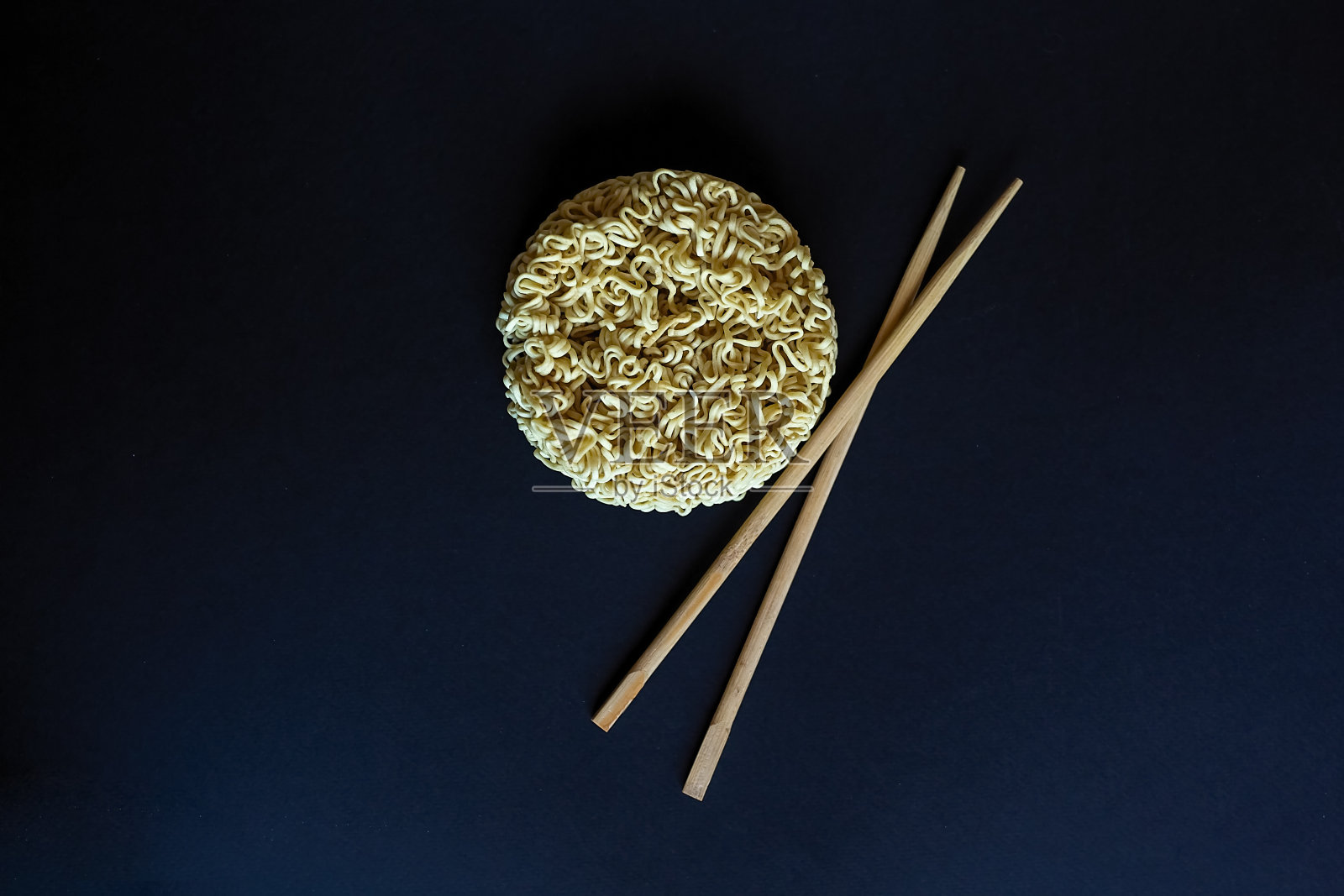 黑色背景上用筷子夹着生方便面。意大利面，为准备这是足够的倒他们与沸水和等待几分钟。副本的空间。照片摄影图片