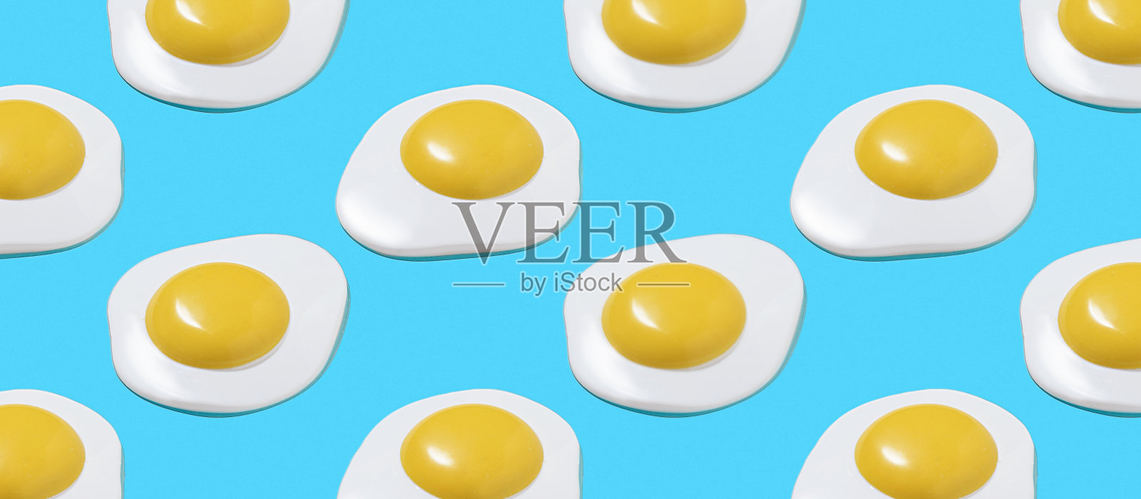 亮蓝色背景上的假鸡蛋图案。照片摄影图片
