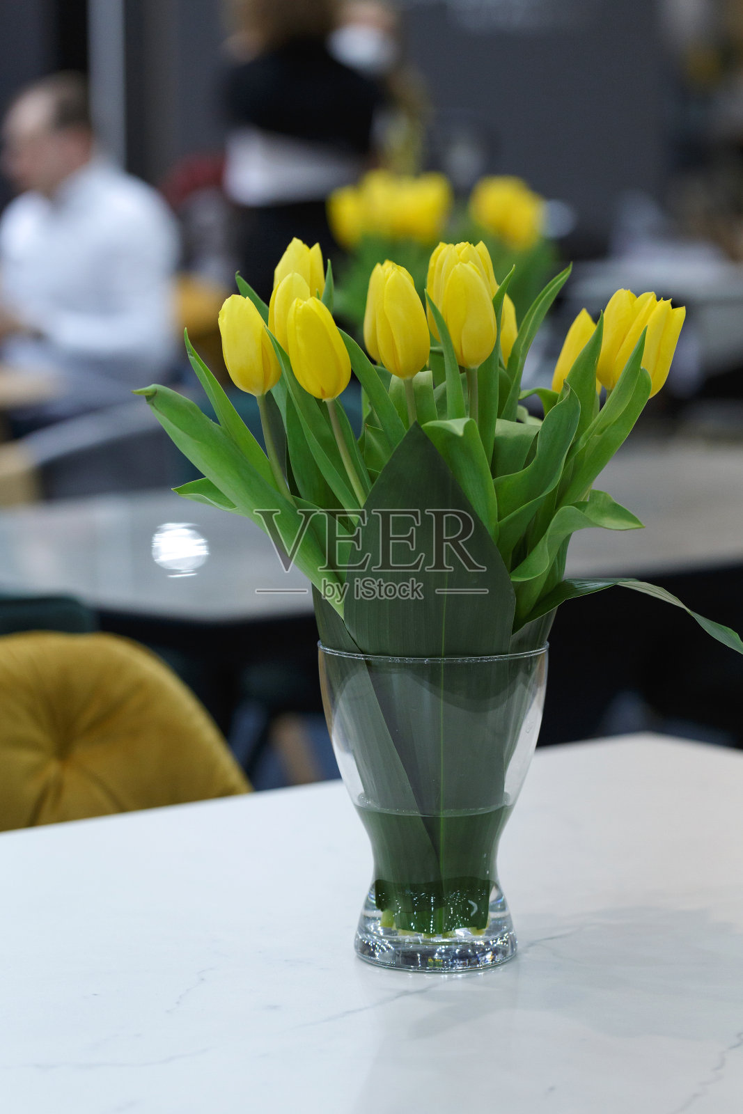 黄色郁金香花束在透明的花瓶里。照片摄影图片