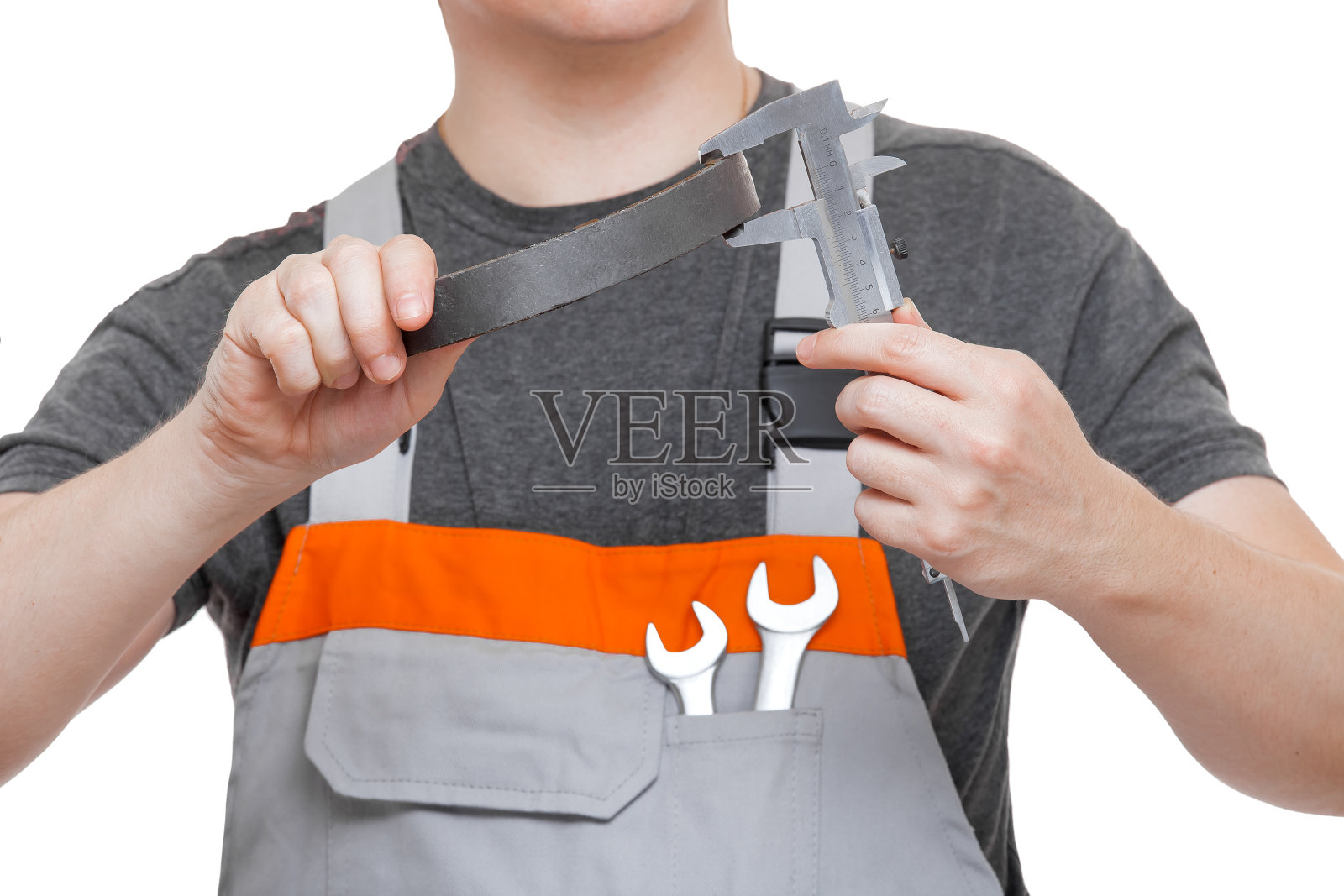 机修工穿着制服，手拿卡钳，用工程师工具在白色背景上仔细测量汽车刹车片零件的石棉尺寸。照片摄影图片