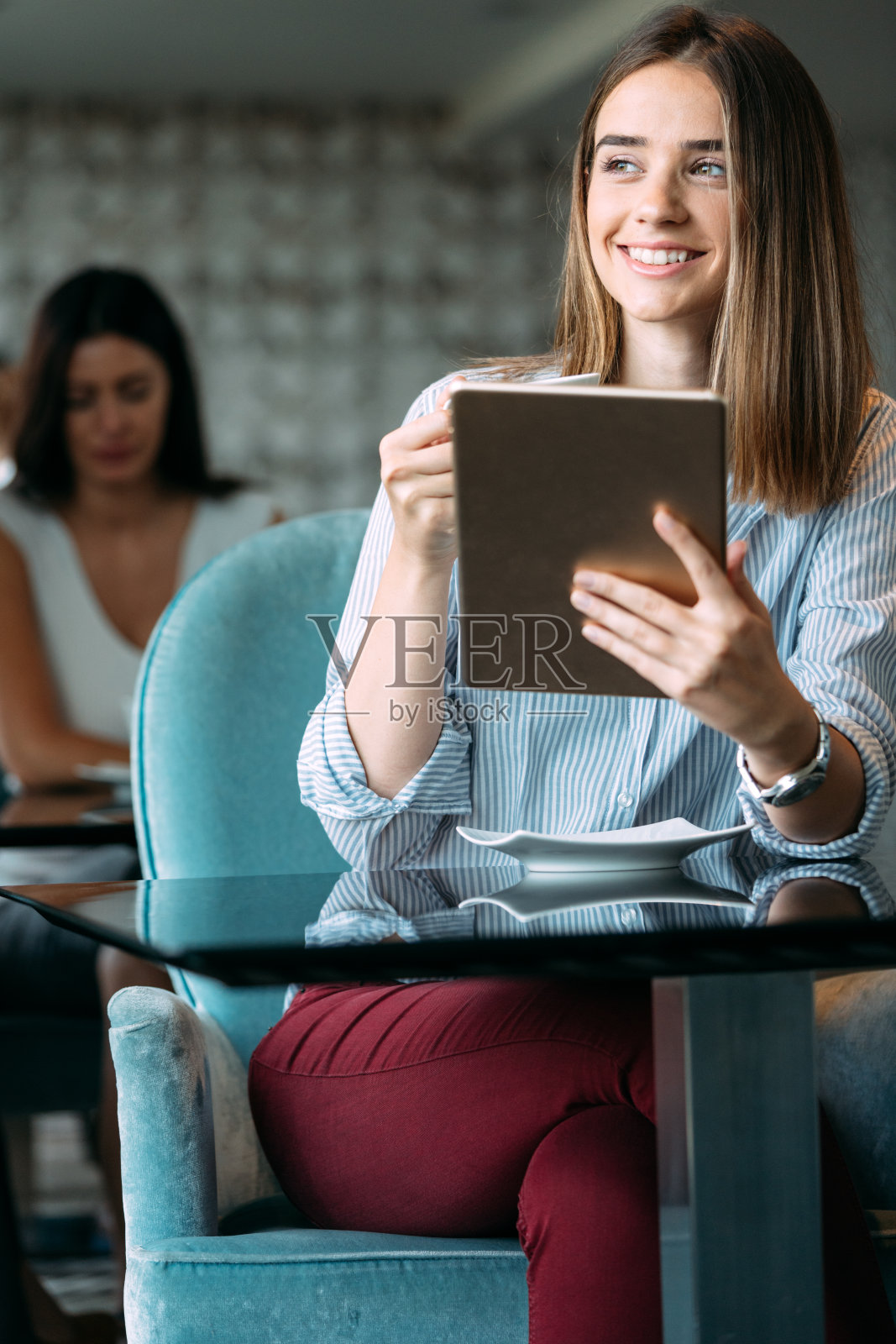 快乐的女经理拿着平板电脑坐在咖啡厅里照片摄影图片