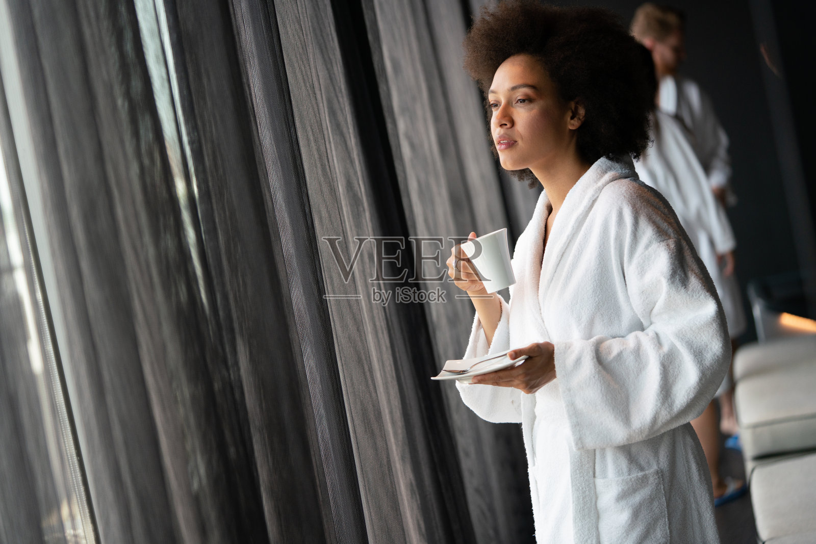 一个美丽的年轻健康的黑人妇女的肖像放松在一个长袍和喝咖啡照片摄影图片