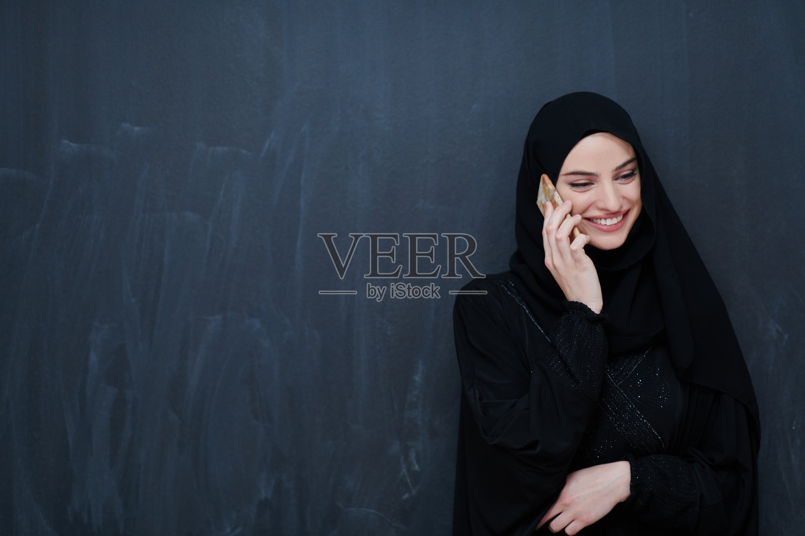 穿着传统服装或长袍的年轻穆斯林女商人使用智能手机照片摄影图片