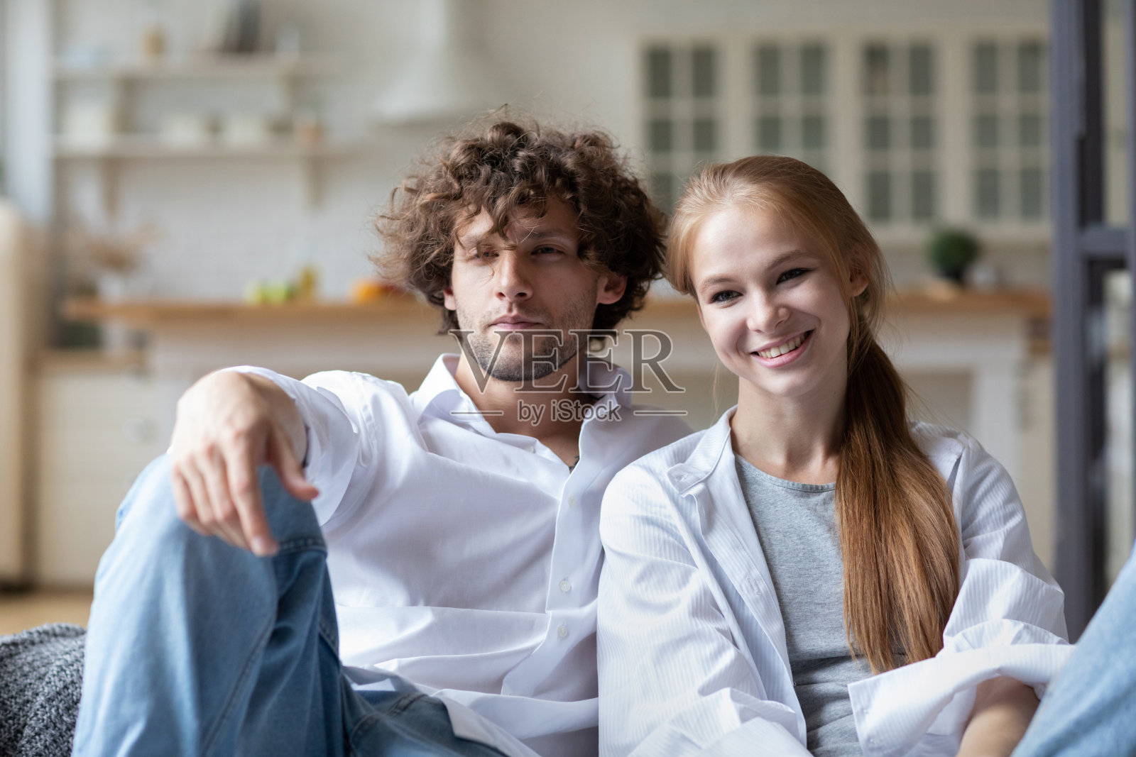 一对年轻夫妇坐在沙发上看镜头。享受在一起。照片摄影图片