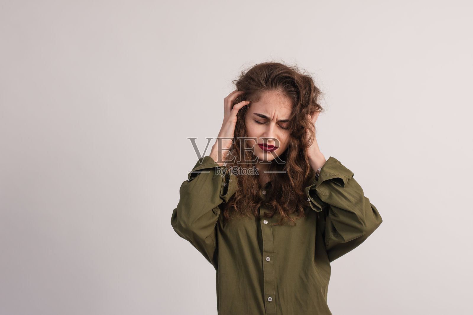 一个年轻漂亮的女人在灰色背景下的头痛照片摄影图片