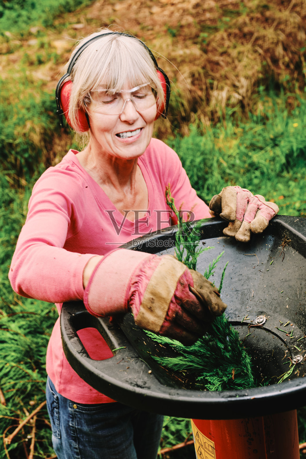 在花园里用电动碎纸机的女人照片摄影图片