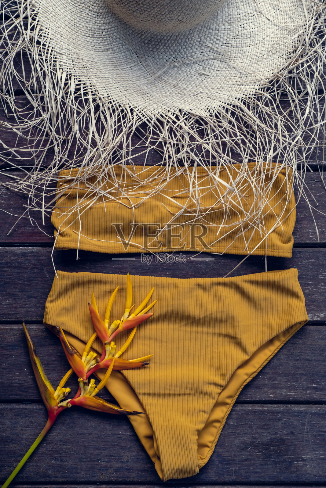 俯视图黄色比基尼泳装泳装与海滩草帽在乡村木制背景。暑假的概念。平躺照片摄影图片