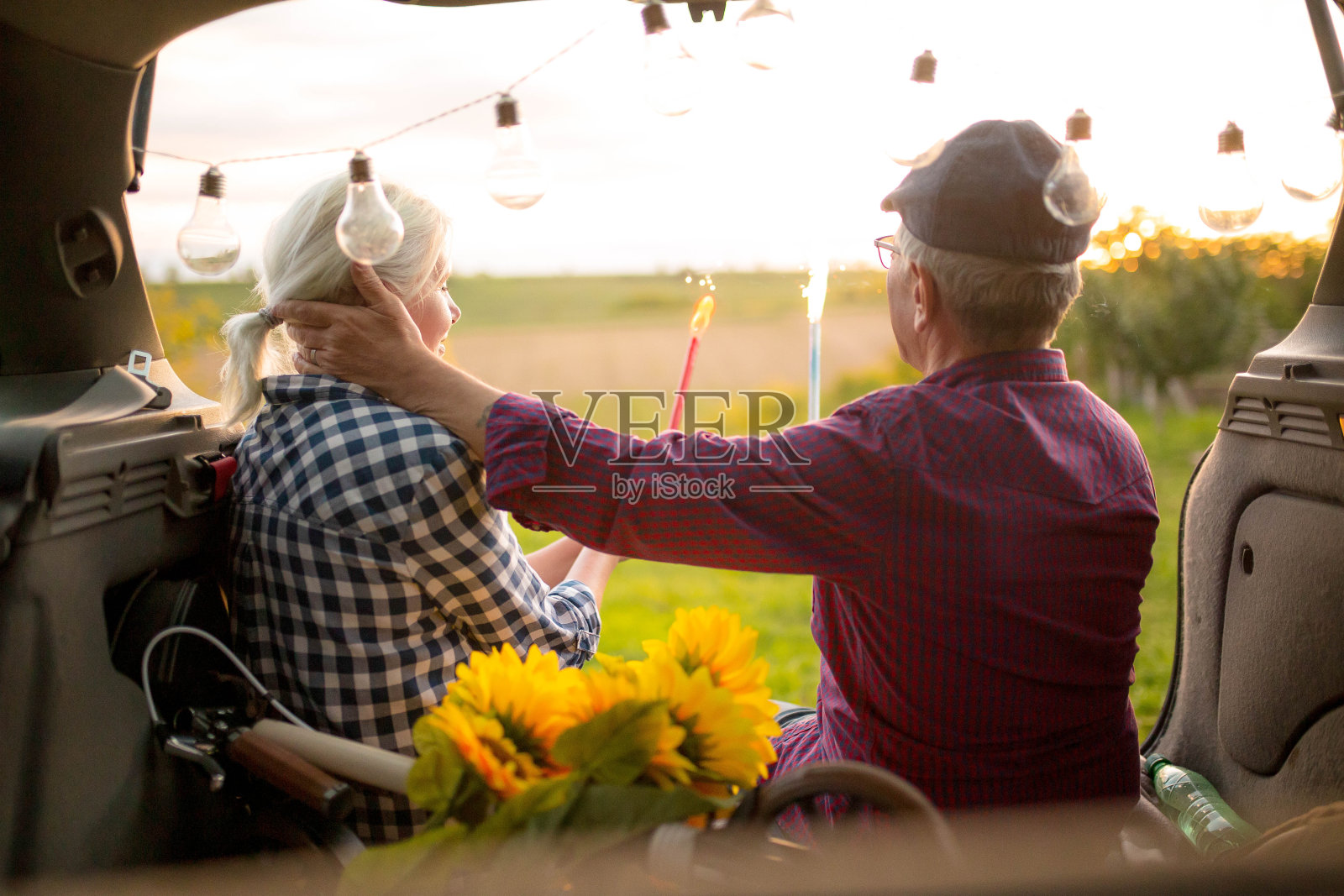 一对快乐的老夫妇坐在他们的汽车后备箱里照片摄影图片