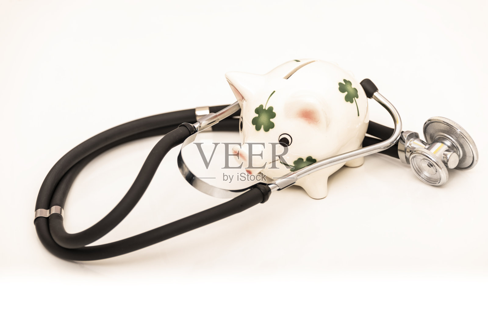 白色背景上，听诊器环绕着储蓄罐照片摄影图片