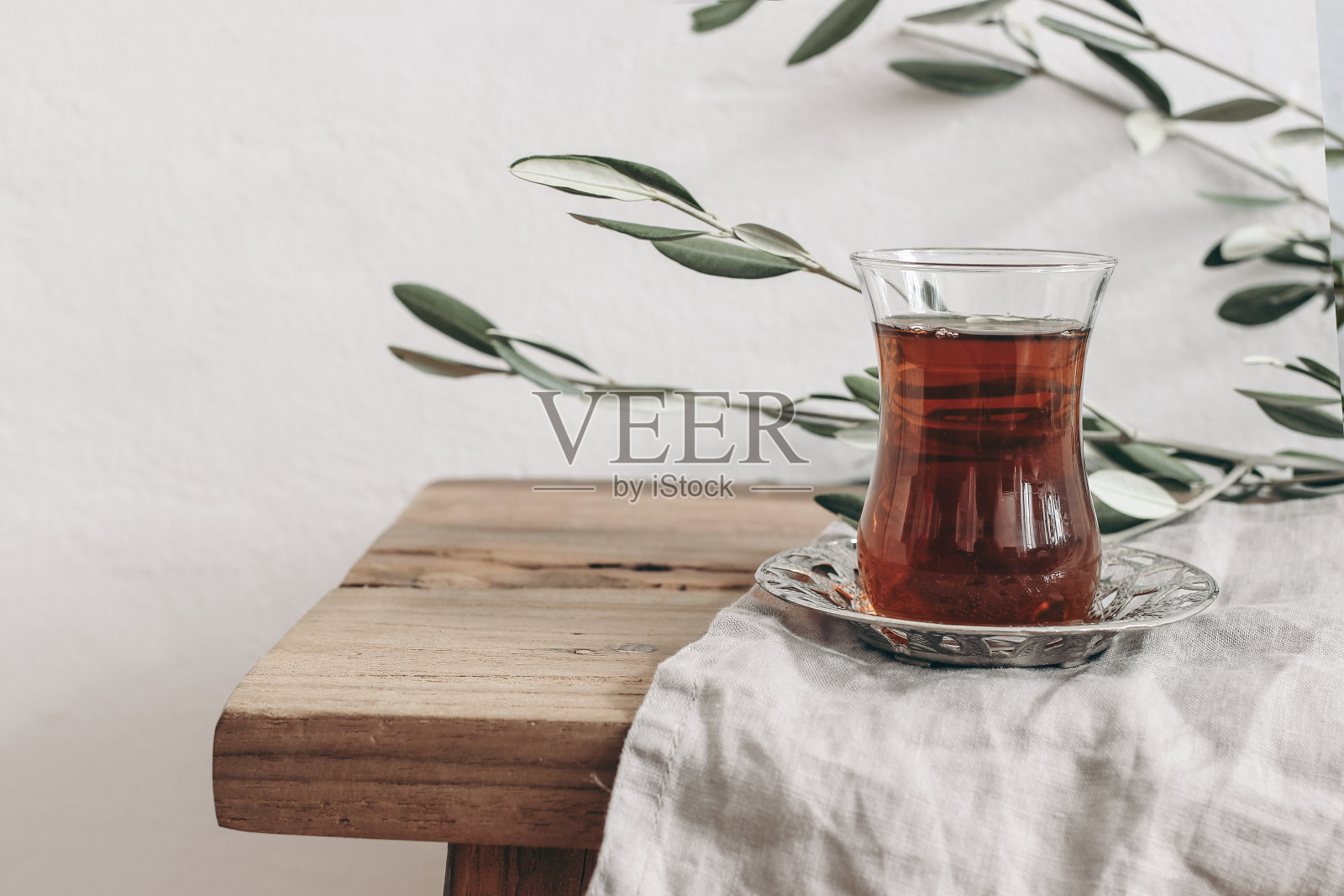 特写土耳其红茶在银碟上的玻璃杯。斋月卡里姆贺卡，请帖。旧木桌的背景上是绿色的橄榄枝。穆斯林开斋饭的概念。前视图。照片摄影图片