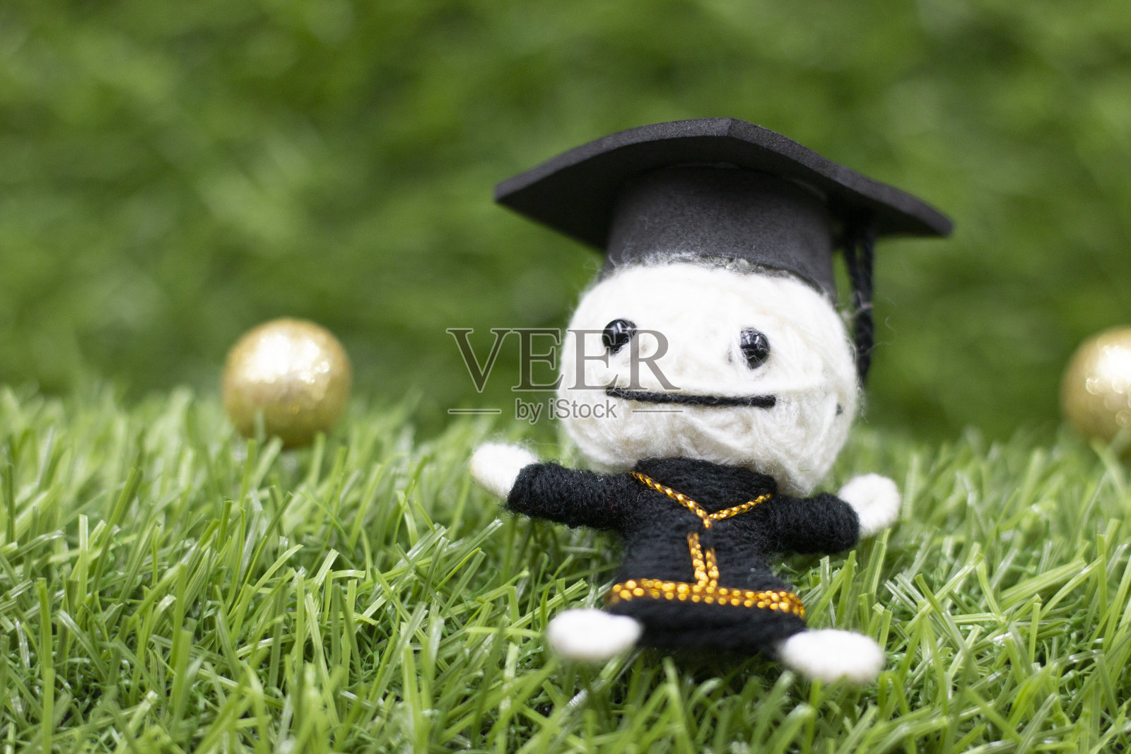 带着流浪汉的帽子和长袍，在绿草如茵的草地上毕业照片摄影图片