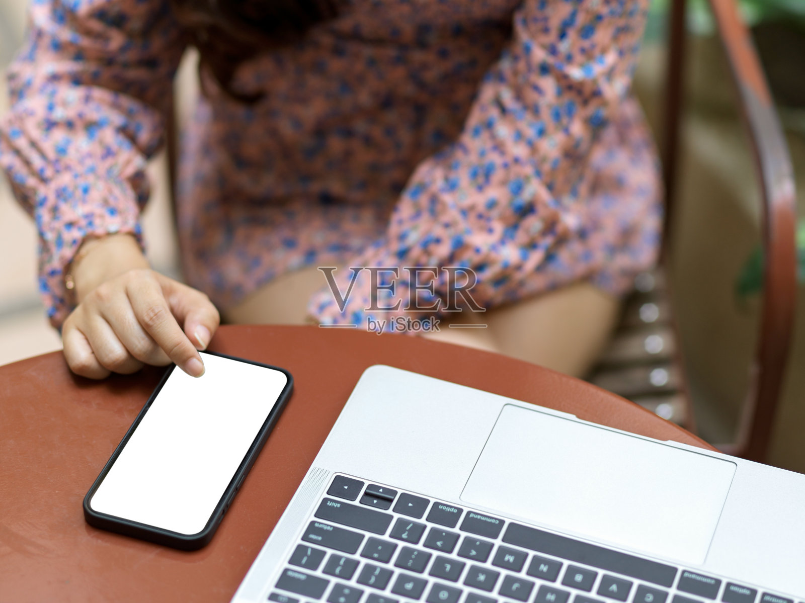 女性在美丽的春装触摸模拟智能手机屏幕在圆桌与笔记本电脑在咖啡馆照片摄影图片