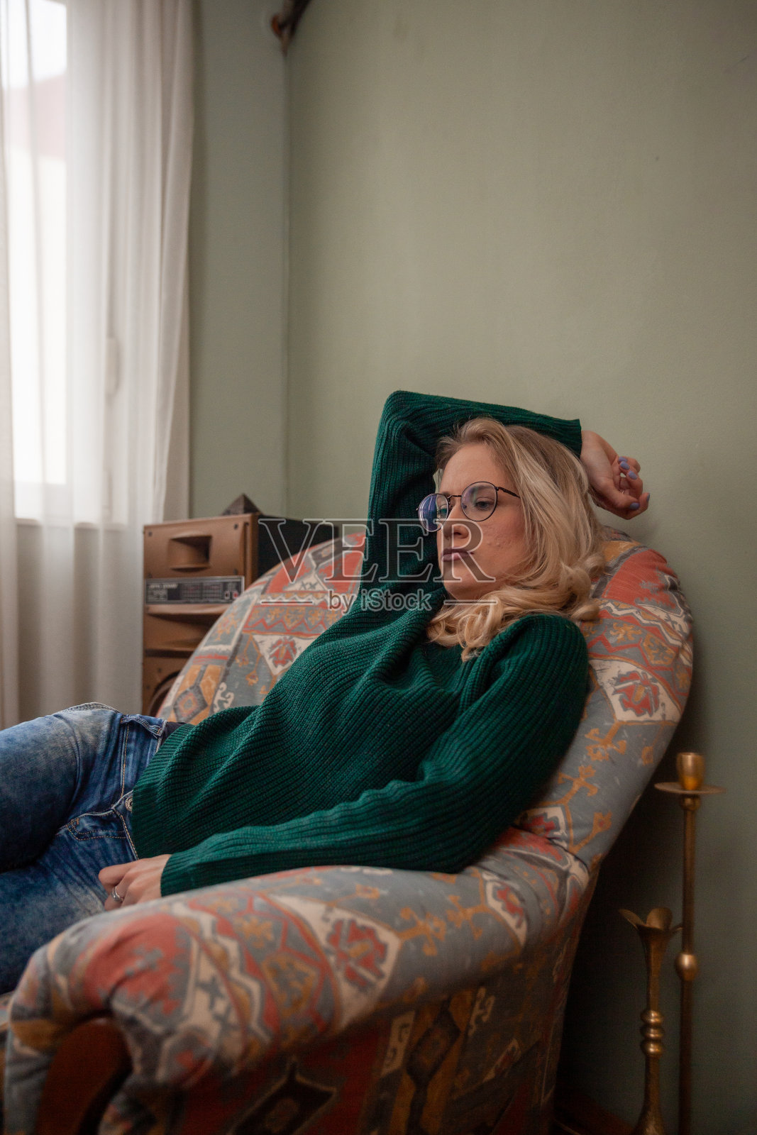 一个年轻的女人，坐在家里的沙发上，看起来很无聊。照片摄影图片