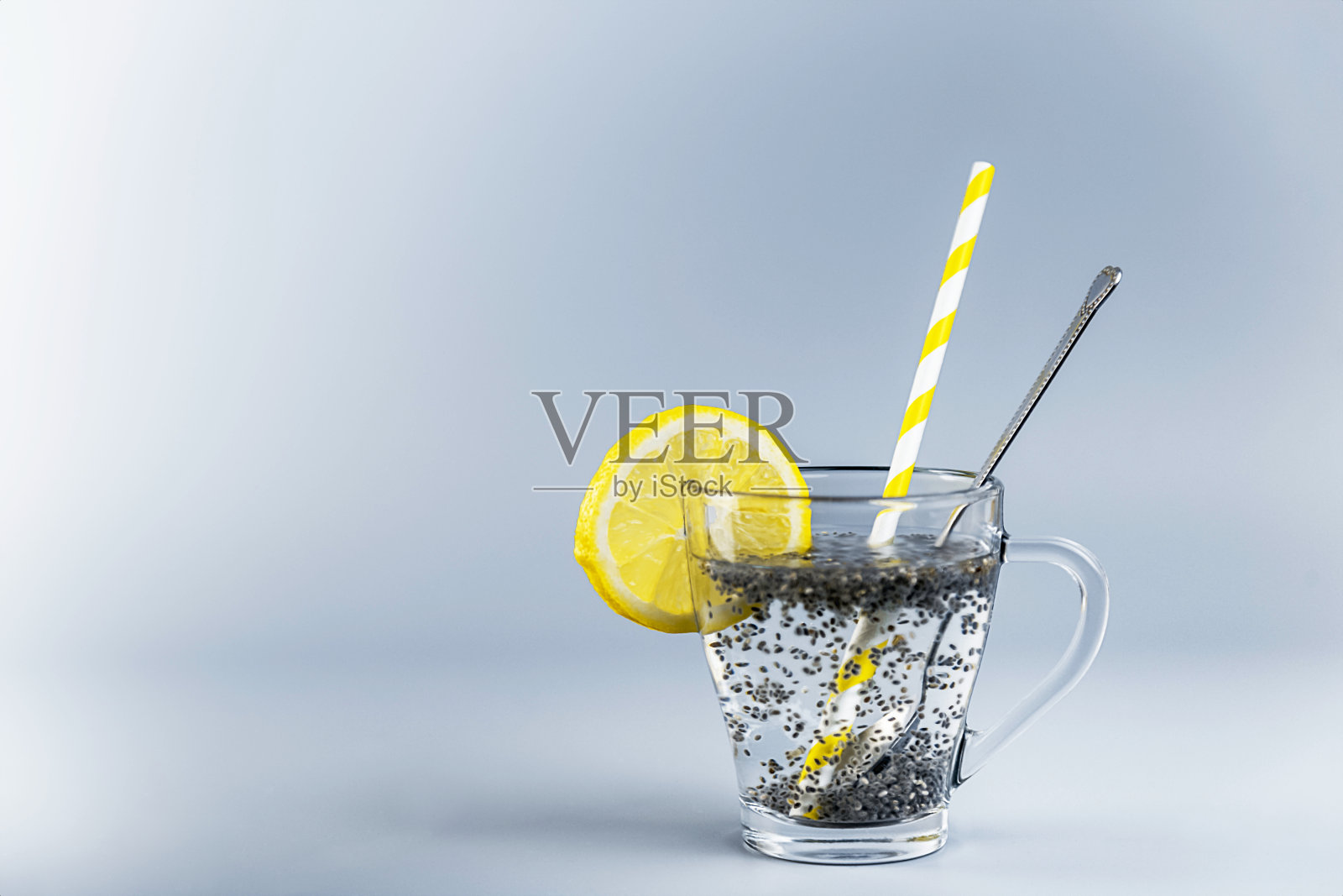 奇亚柠檬水在玻璃杯中与柠檬片，饮用吸管和勺子照片摄影图片