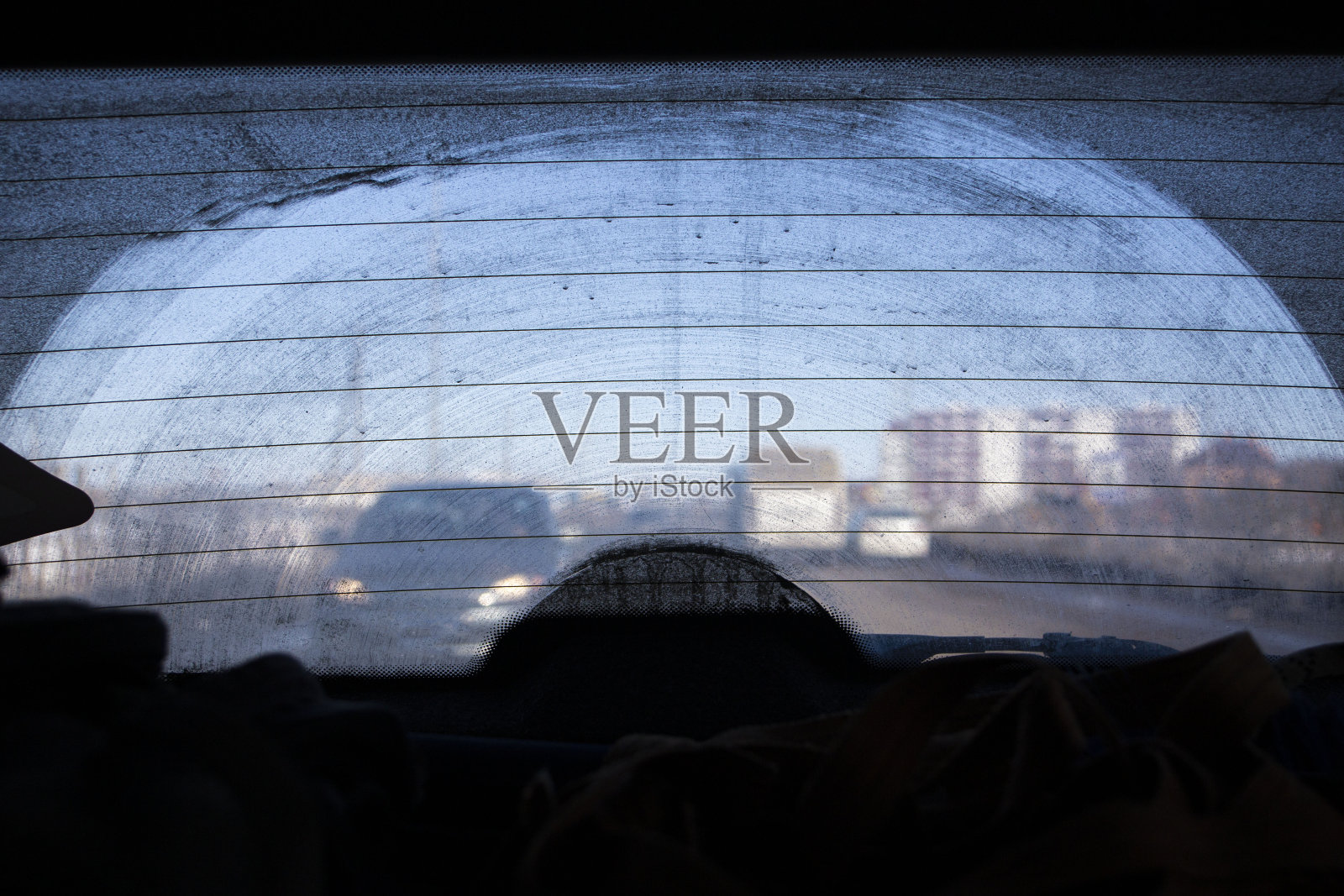 一辆车的后窗很脏，从乘客舱看向路面，车头和背景因散景效果而模糊照片摄影图片