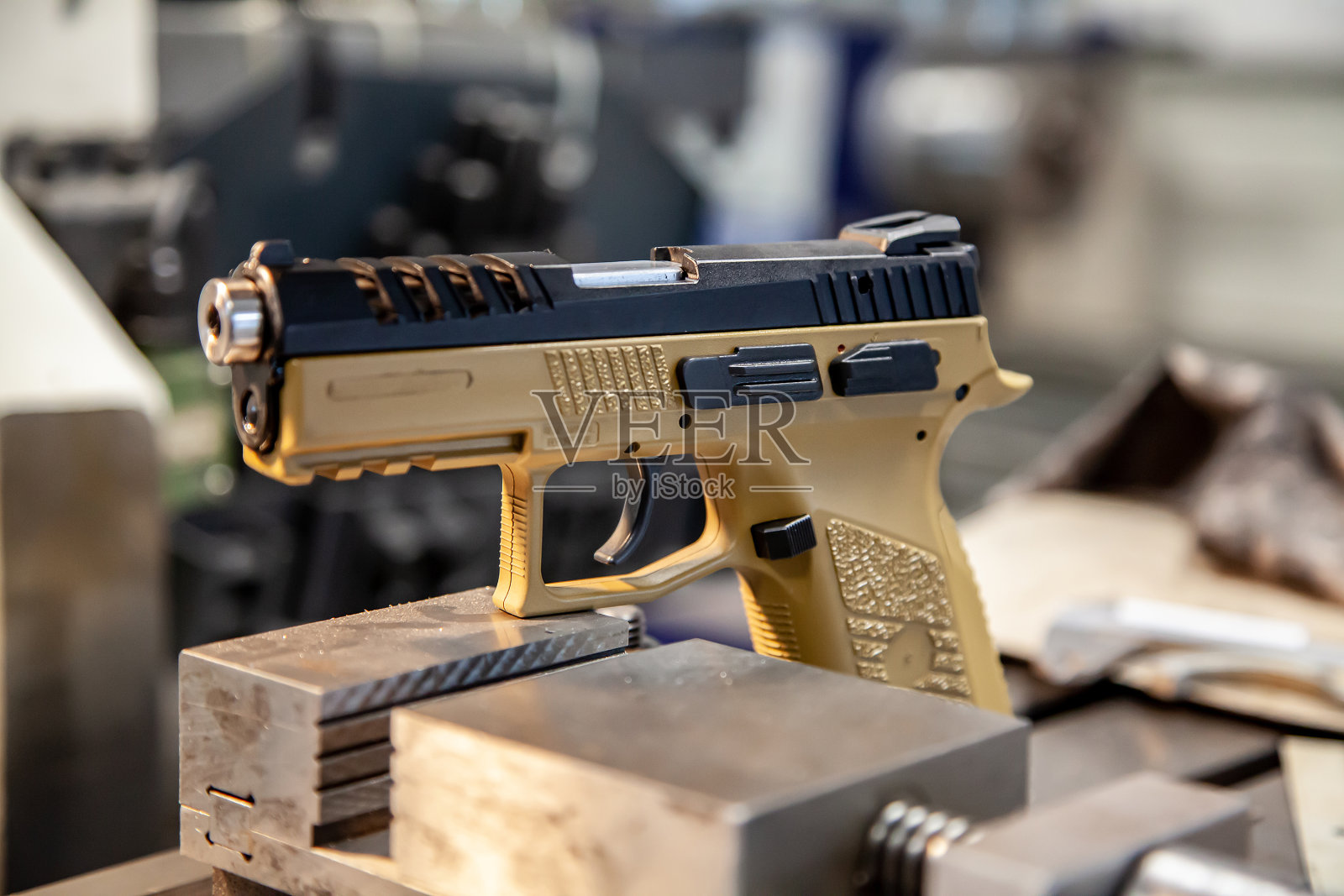 在车间的工作台上有一把米色手柄的现代手枪。武器维修。手枪修复。照片摄影图片