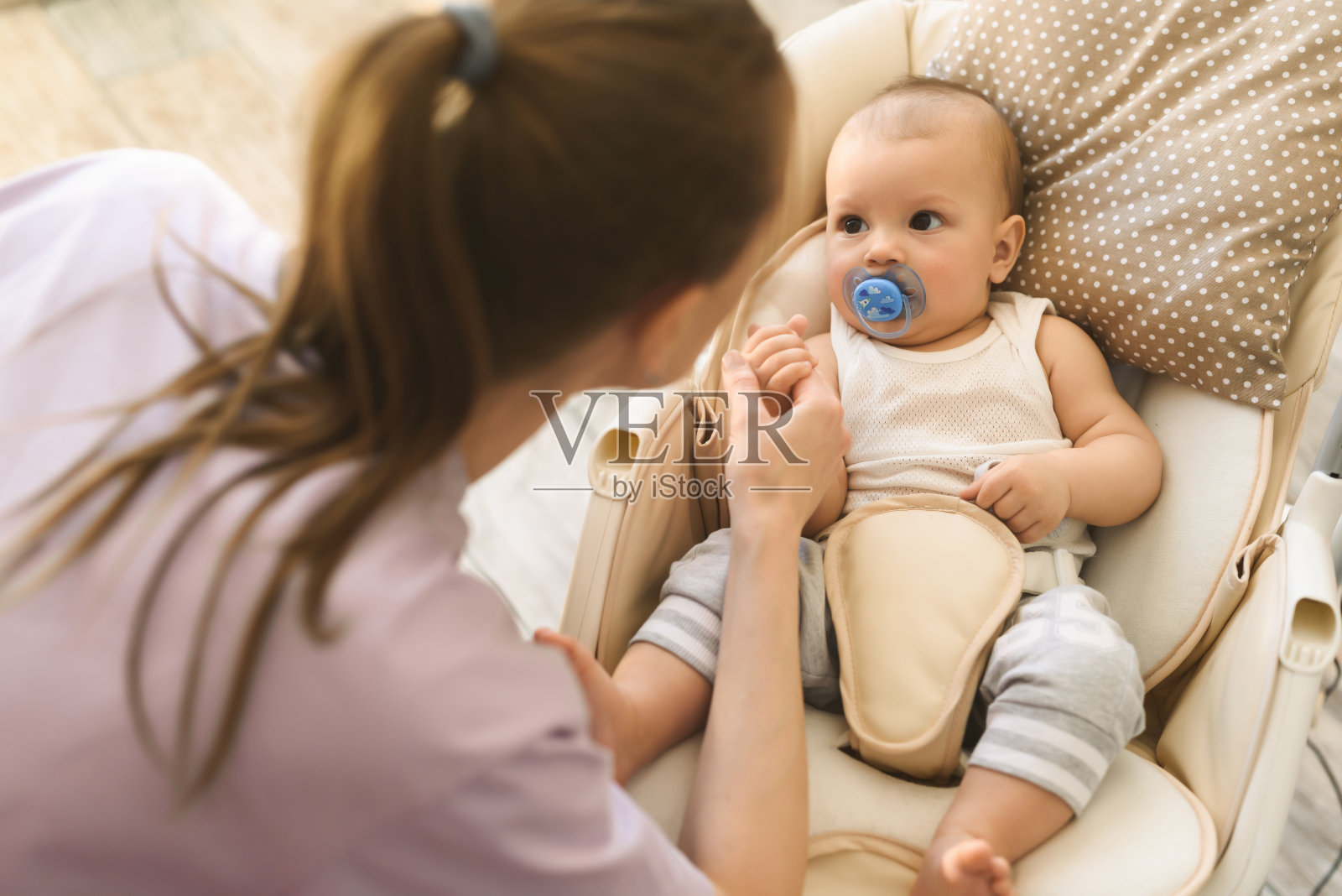 母亲把孩子放在孩子的电动摇篮里睡觉。做母亲和组建家庭的幸福照片摄影图片