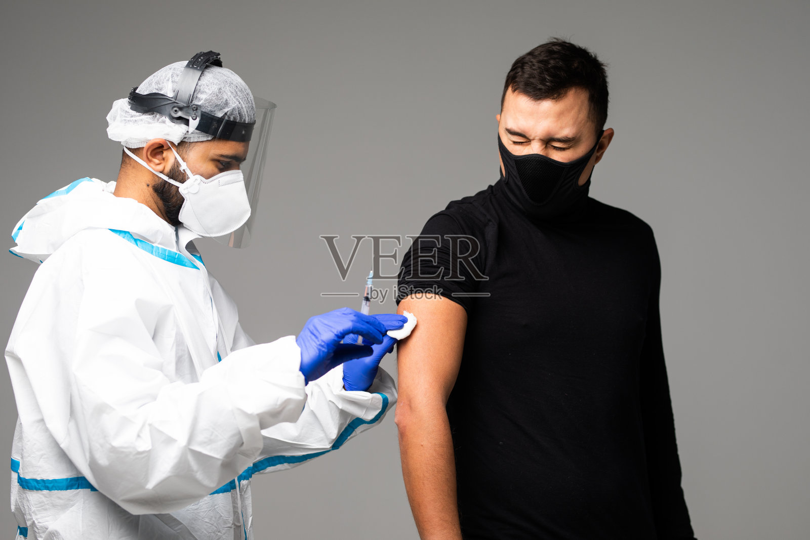 医护人员用疫苗注射器向白种人手臂肌肉注射COVID-19疫苗，进行COVID-19免疫接种。2019冠状病毒病疫苗接种，选择性重点照片摄影图片