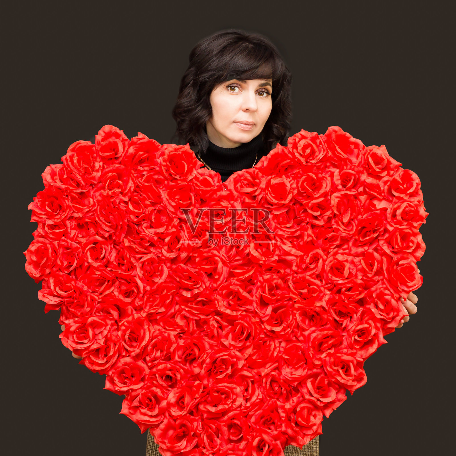 一个漂亮的黑发女人，手里拿着一大束心形的花照片摄影图片